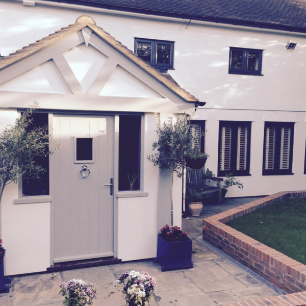 Front of large modern property with white exterior walls and black window frames